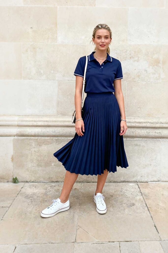 Navy-pleated-midi-skirt-+-team-colored-polo-shirt-+-white-leather-sneakers-+-crossbody-bag-+-simple-jewelry